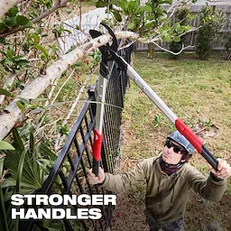 A person is using a 2" Lopper to cut a tree branch. The long-handled tool has red grips and is positioned over a fence. The image features text stating "STRONGER HANDLES" in bold white letters, emphasizing the durability of the handles.