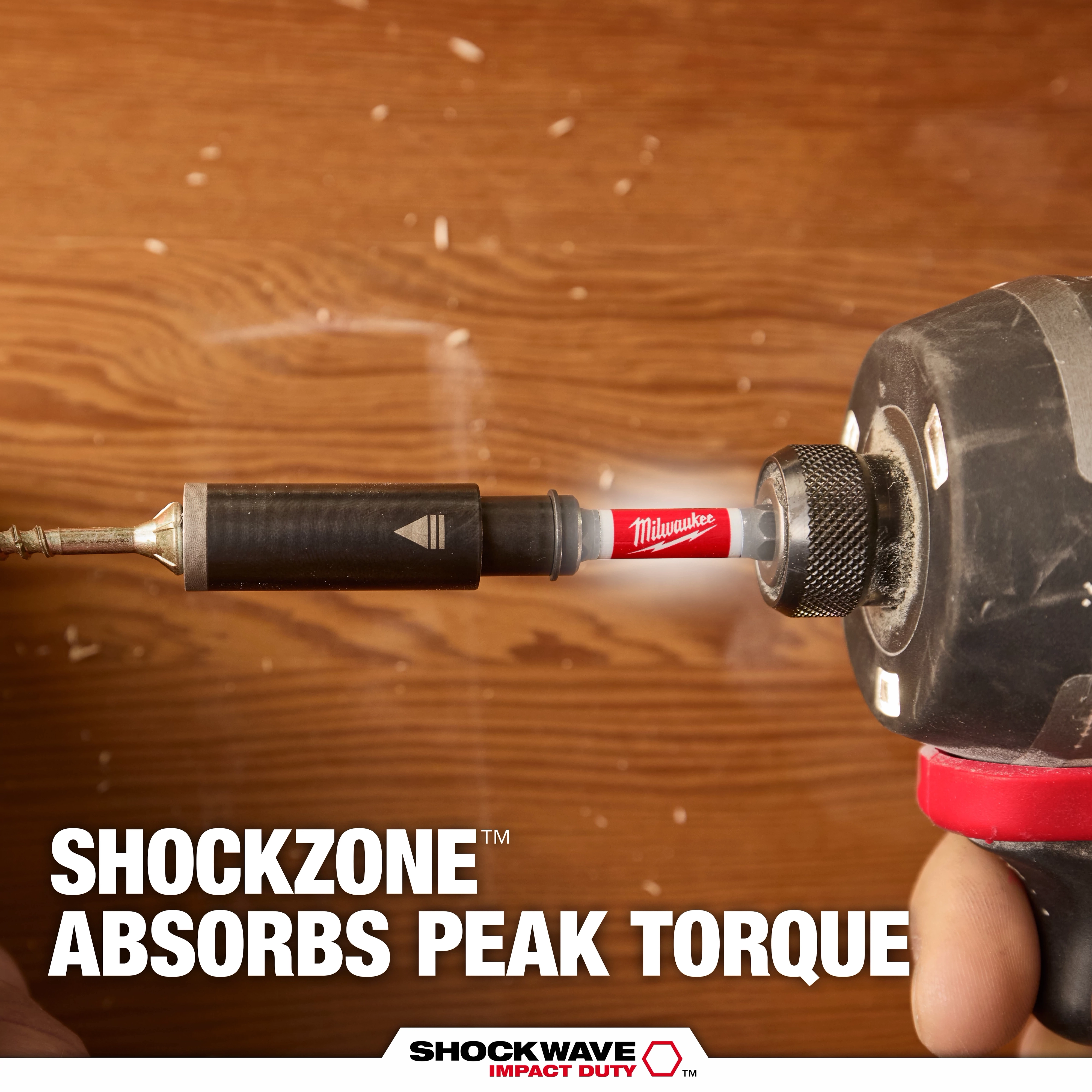 A person uses a power drill with a red Milwaukee SHOCKWAVE bit to drill into wood. The text reads "SHOCKZONE ABSORBS PEAK TORQUE," highlighting the tool's ability to manage torque impact.