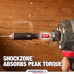 A person uses a power drill with a red Milwaukee SHOCKWAVE bit to drill into wood. The text reads "SHOCKZONE ABSORBS PEAK TORQUE," highlighting the tool's ability to manage torque impact.