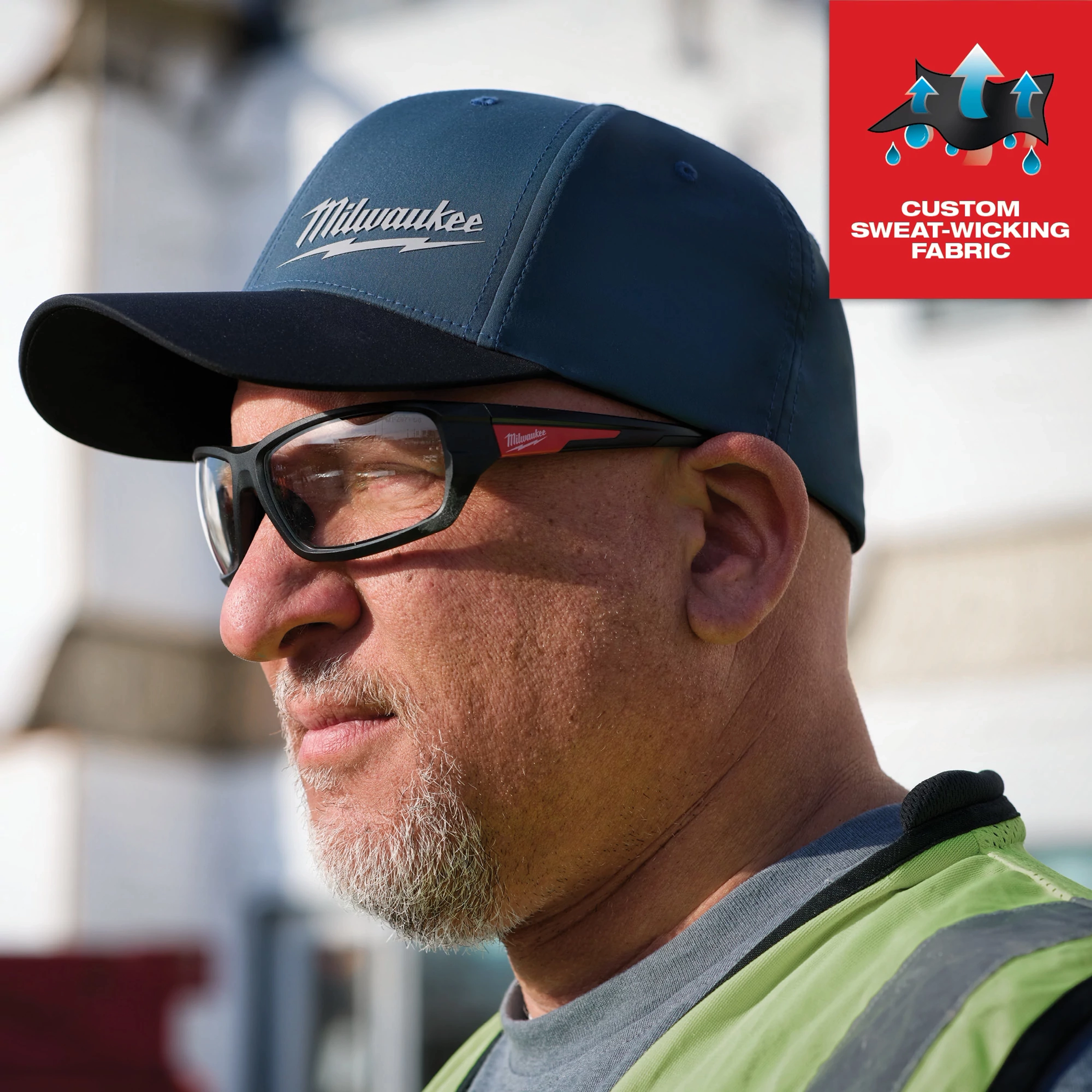 WORKSKIN Performance Fitted Hat in Blue shown on a person, highlighting its custom sweat-wicking fabric feature.