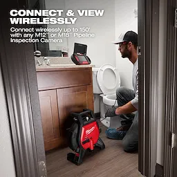 A person is kneeling in a bathroom beside a toilet, working with a Milwaukee pipeline inspection camera. The camera equipment is on the floor, and a monitor is on the sink. Text on the image advertises wireless connection up to 150 feet with M12 or M18 pipeline inspection cameras.