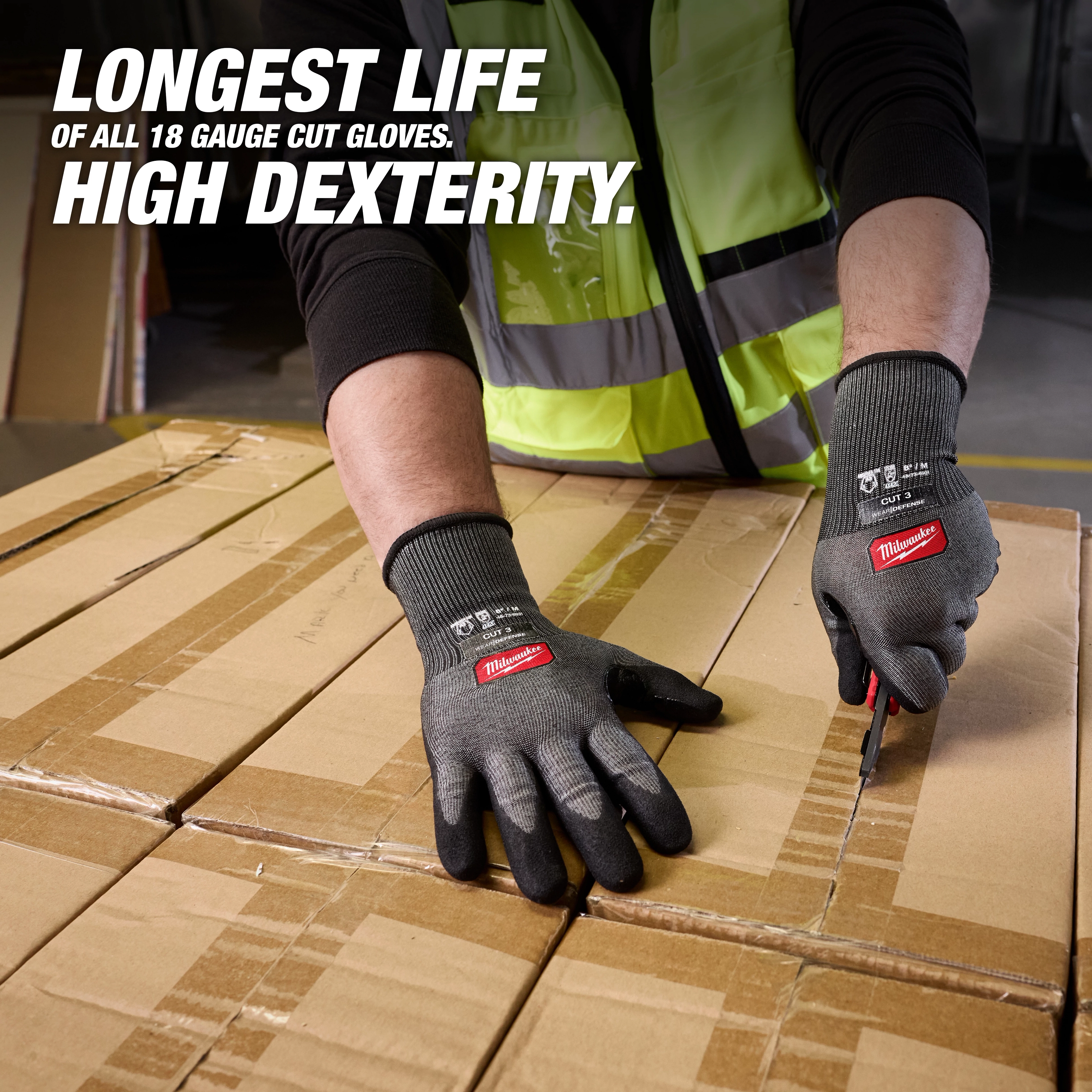 Hands wearing Cut Level 3 High Dexterity Nitrile Dipped Gloves w/ WEAR-DEFENSE Protection cutting cardboard boxes.