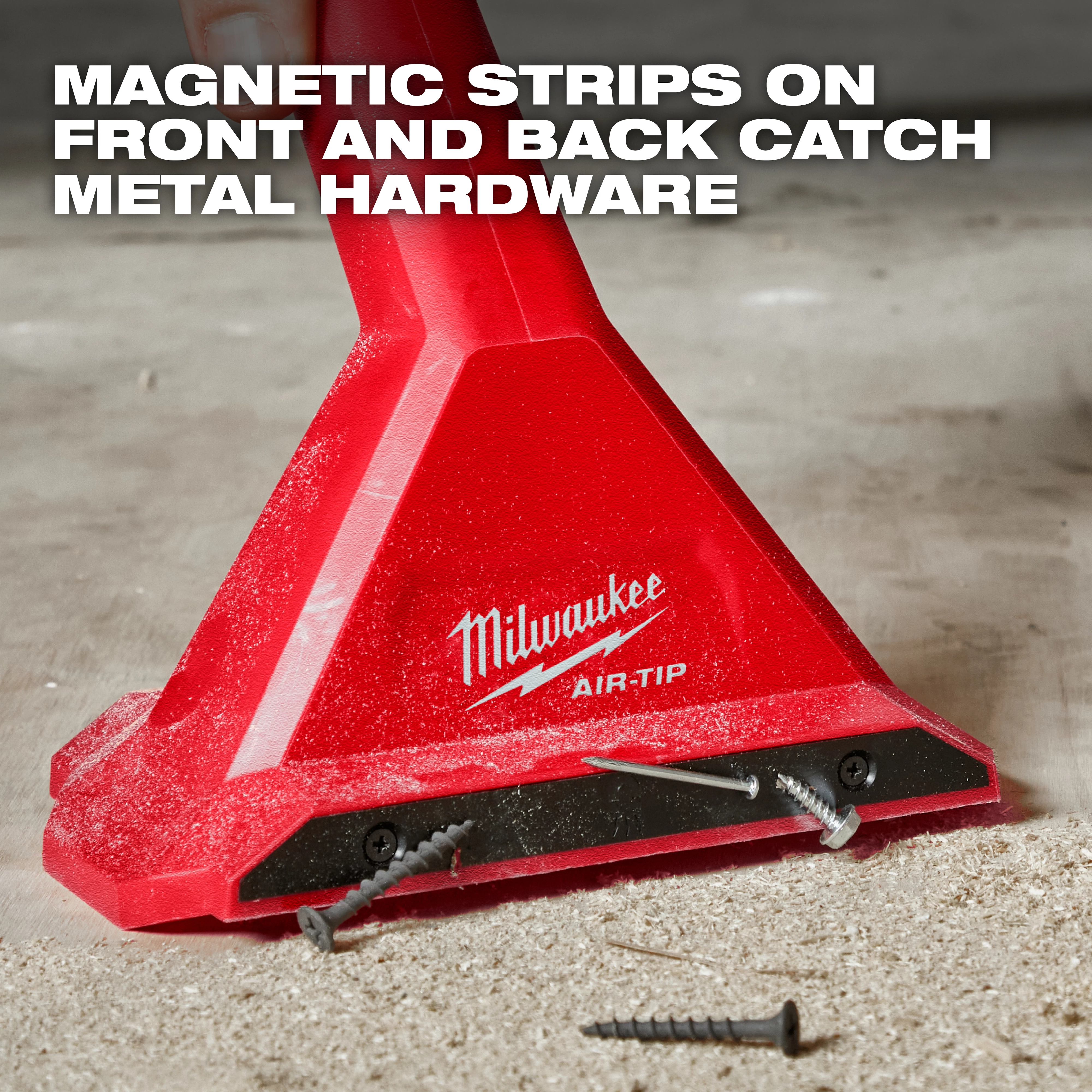 The image shows an AIR-TIP™ Magnetic Utility Nozzle by Milwaukee. The red nozzle has magnetic strips on the front and back, effectively catching metal hardware like screws on a dusty surface. The text "MAGNETIC STRIPS ON FRONT AND BACK CATCH METAL HARDWARE" is overlaid at the top.