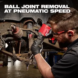 Worker using the red M18 FUEL STRIKER Hammer Chisel on a vehicle suspension assembly.
