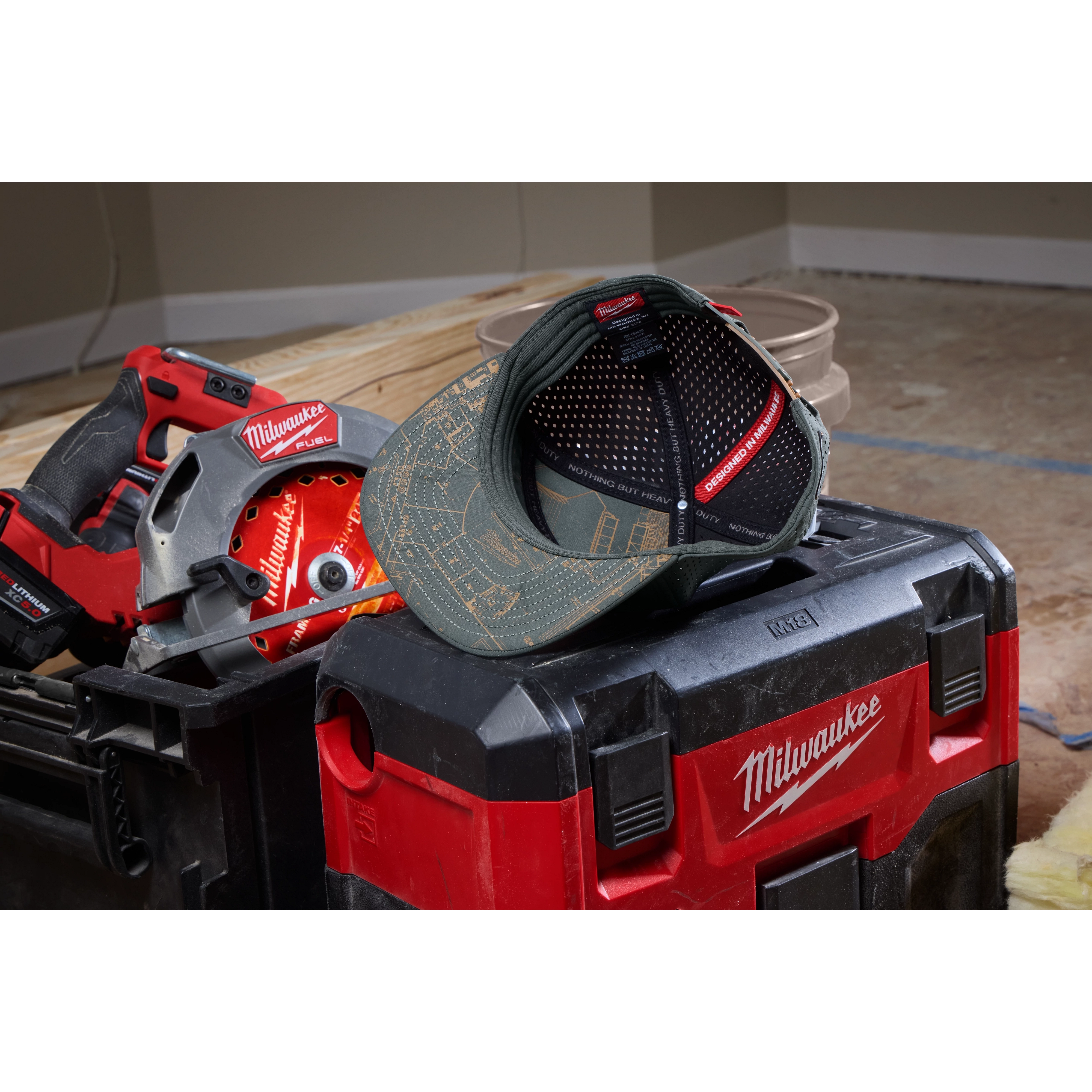 Flat Brim Snapback cap with a printed design, displayed on top of a red and black toolbox next to power tools.