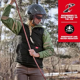 A person dressed in a green shirt and helmet wears the Women's FREEFLEX™ Lightweight Insulated Vest Black, holding a climbing rope outdoors. The vest is advertised as windproof, water-resistant, and engineered for job flexibility.
