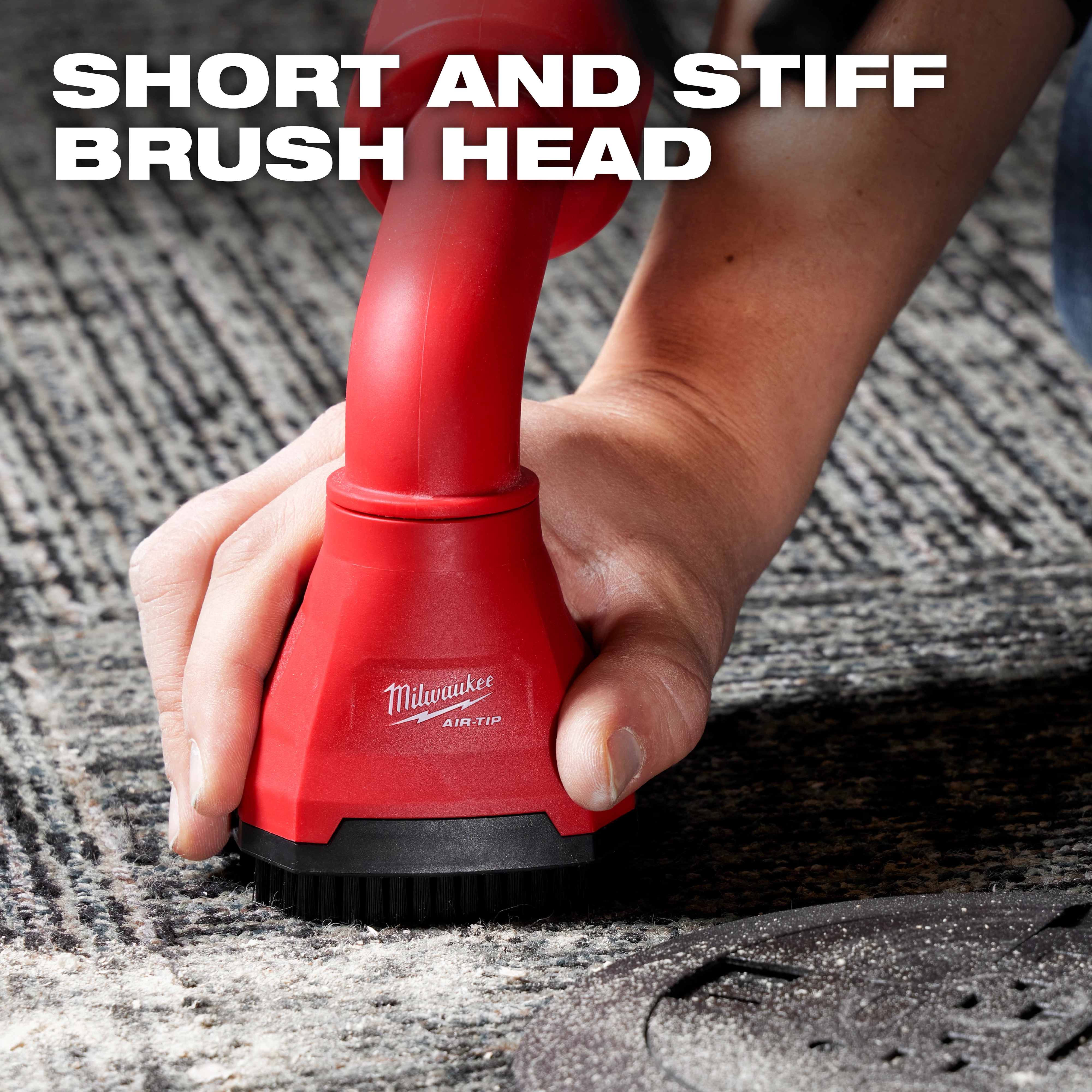 A person uses the red AIR-TIP™ Swiveling Palm Brush on a carpet. The brush features a short and stiff brush head, as noted in the text overlay. The brand logo and product name, Milwaukee AIR-TIP™, are visible on the brush.