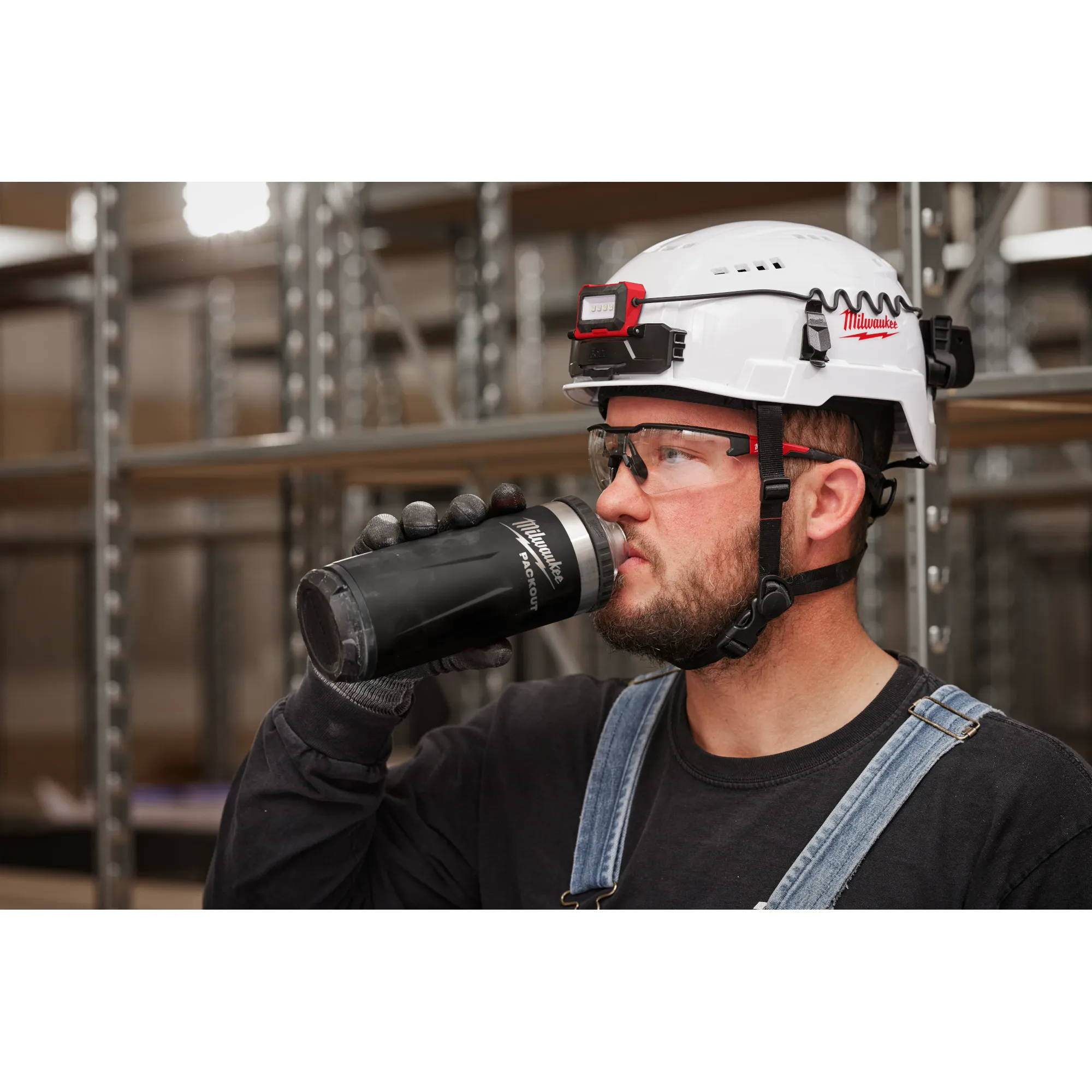 Image of a worker drinking from a Milwaukee PACKOUT Insulated Bottle with Chug Lid in black