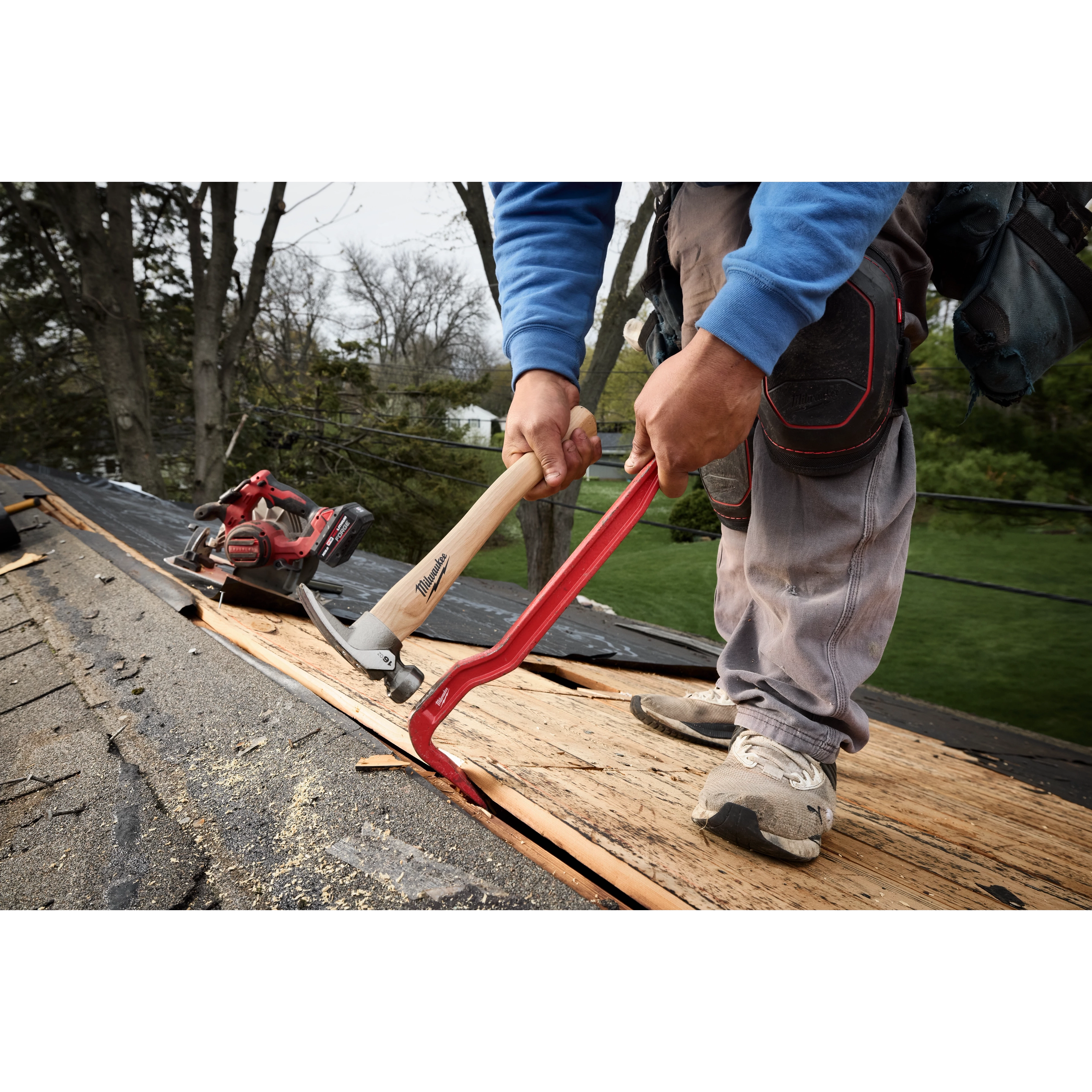 Worker using a 16oz Smooth Face Hickory Handle Hammer and pry bar on roof decking.