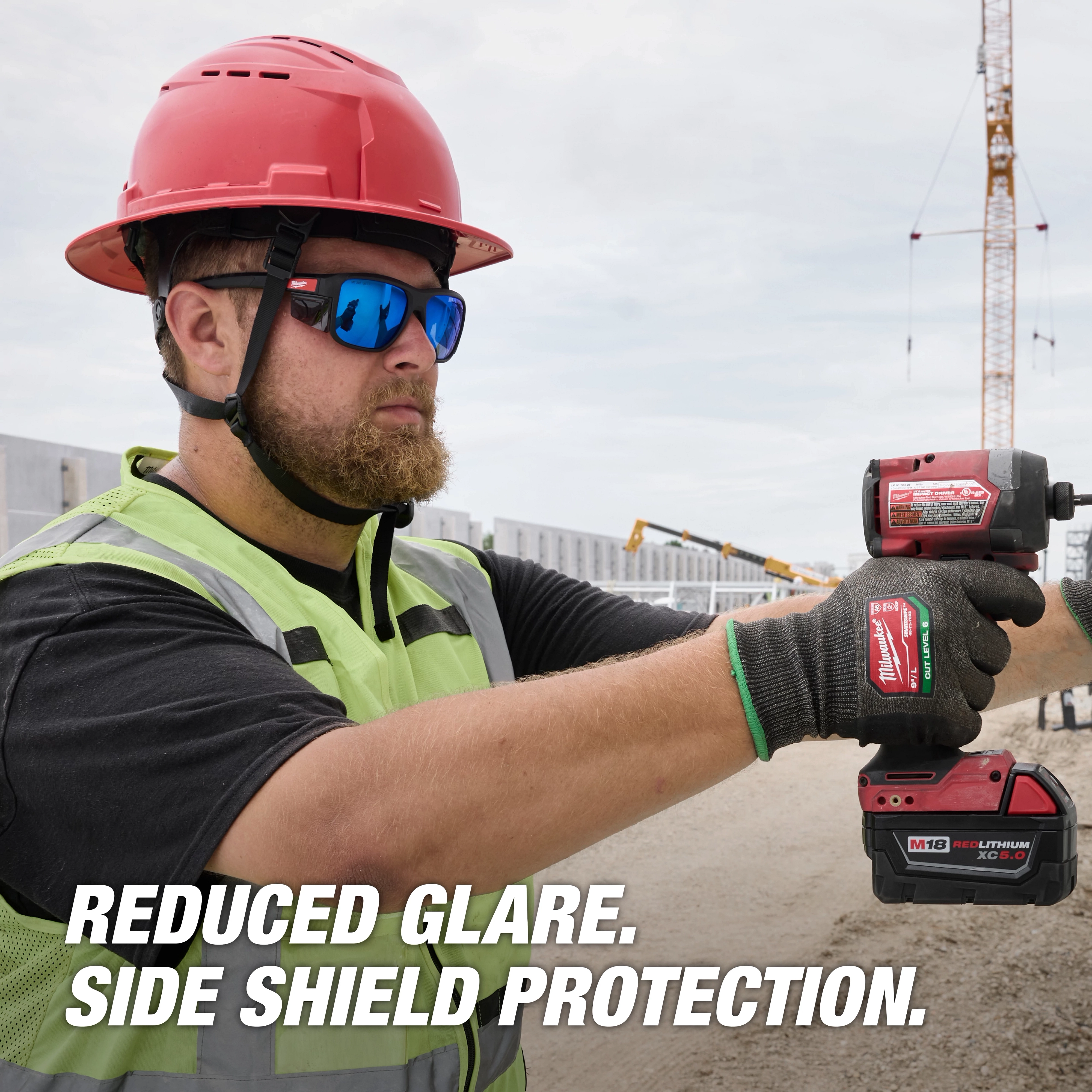 A construction worker wears Polarized Full Frame Safety Glasses with Removable Side Shields – Blue Mirrored Dual Coat Lenses, operating a power tool. The text, "Reduced Glare. Side Shield Protection." is displayed.