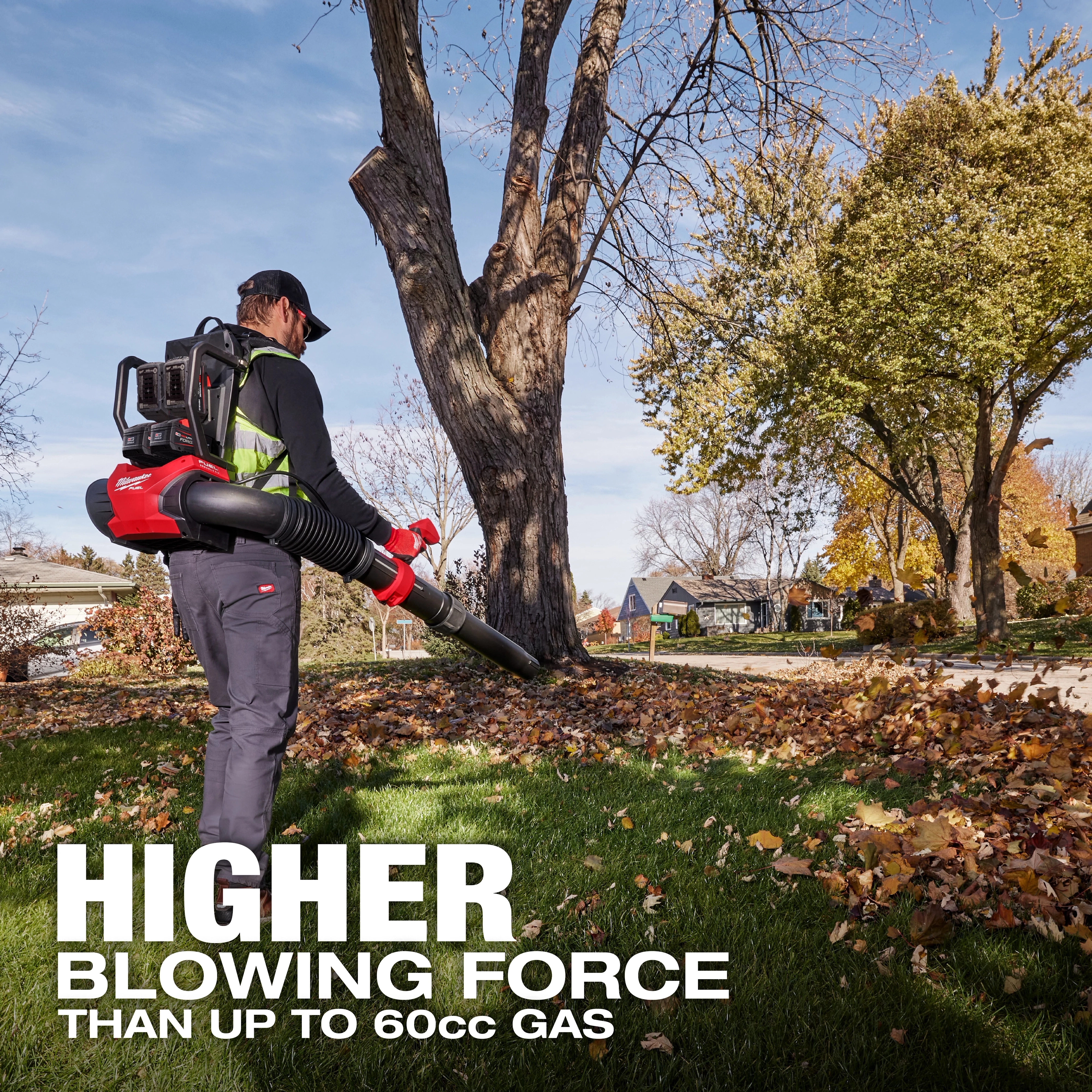 A person uses the M18 FUEL™ Dual Battery Backpack Blower to clear leaves in a residential yard. The text on the image reads: "HIGHER BLOWING FORCE THAN UP TO 60cc GAS." Trees and houses are visible in the background.