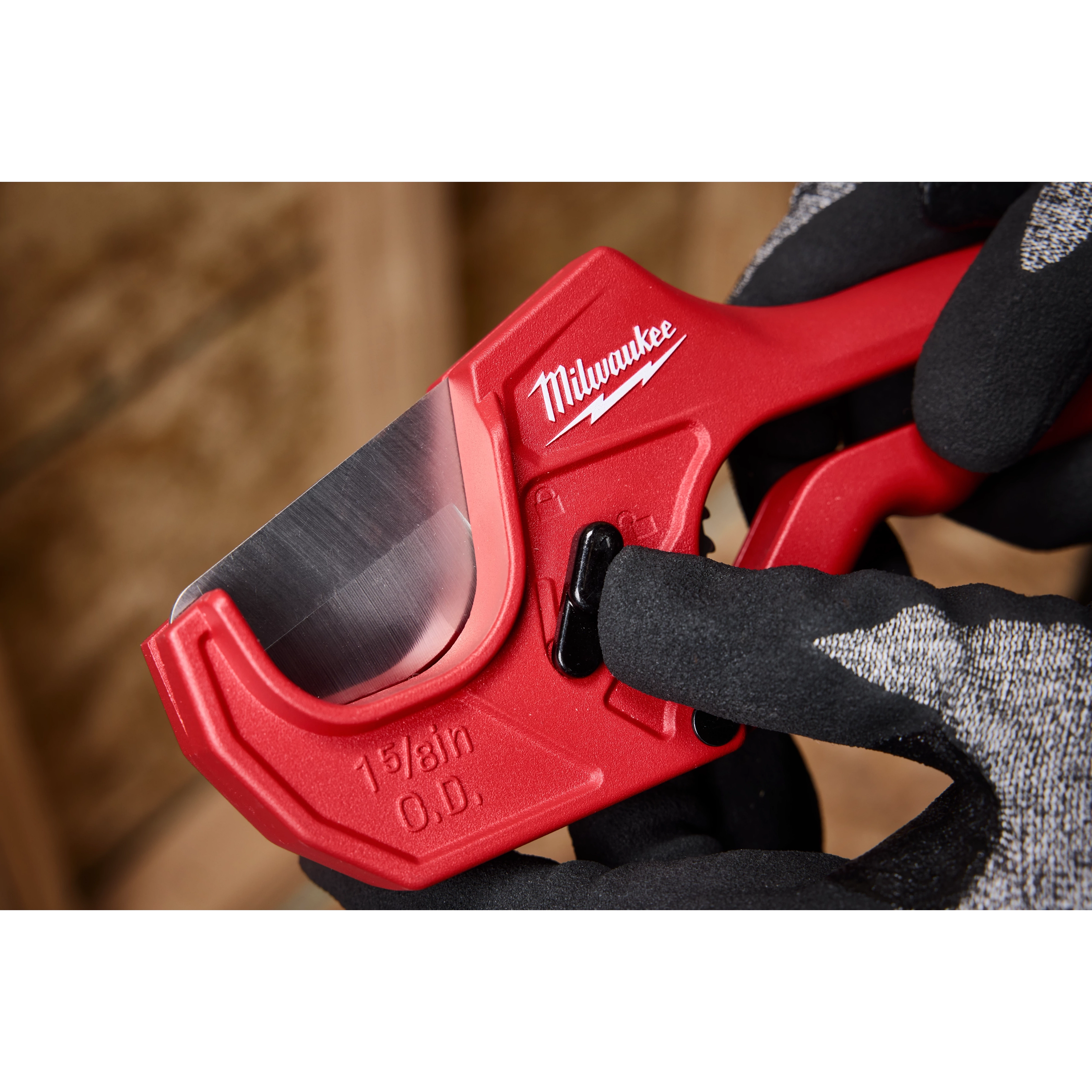 A 1-5/8" ratcheting pipe cutter with a red body is being held by a gloved hand.