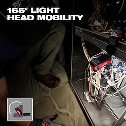 Milwaukee pivoting light illuminates wiring inside an open electrical panel.
