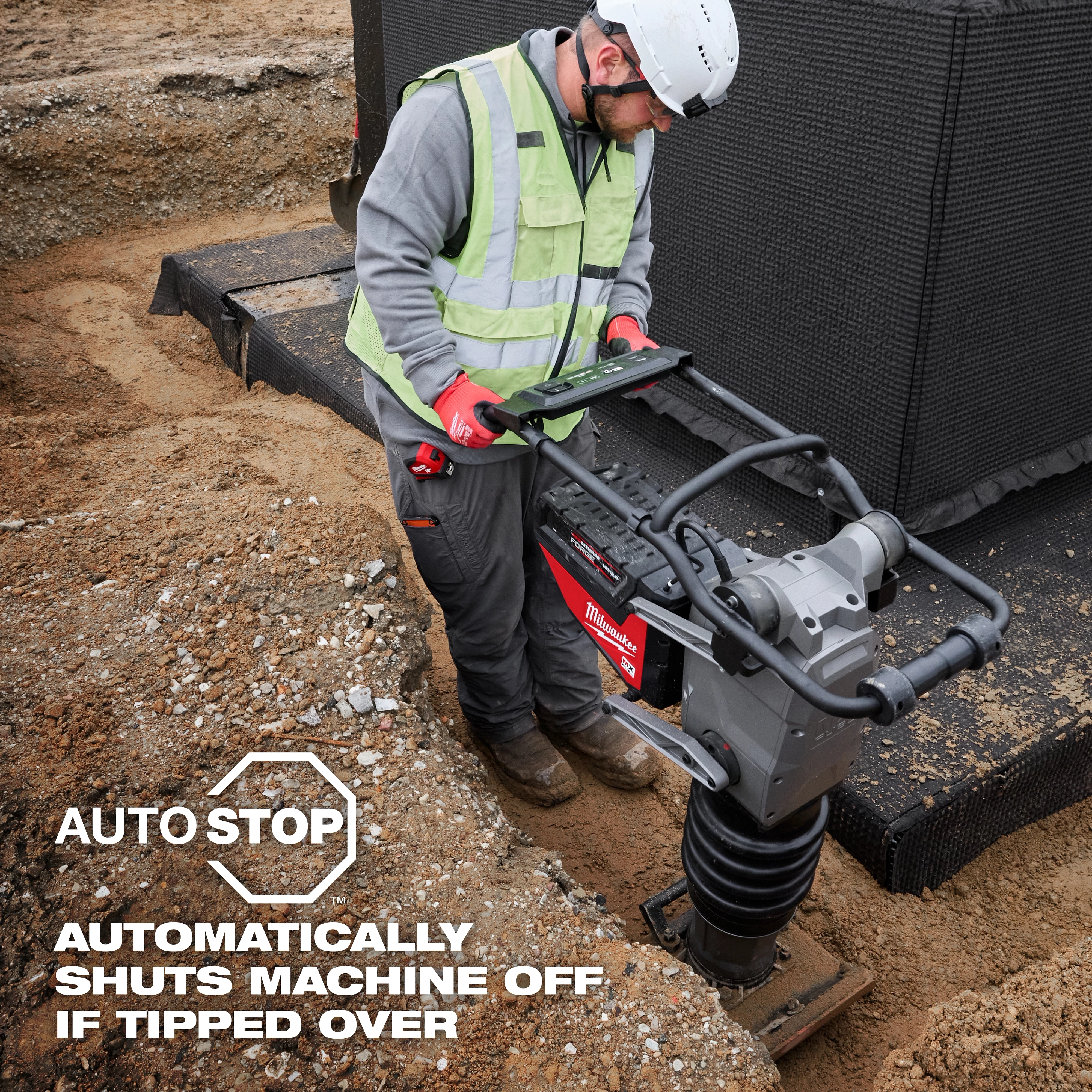 A construction worker operates the MX FUEL™ 70 kg Rammer, standing on a sandy site. Text overlay states, "AUTO STOP: Automatically shuts machine off if tipped over." The worker is wearing safety gear, including a vest and gloves.