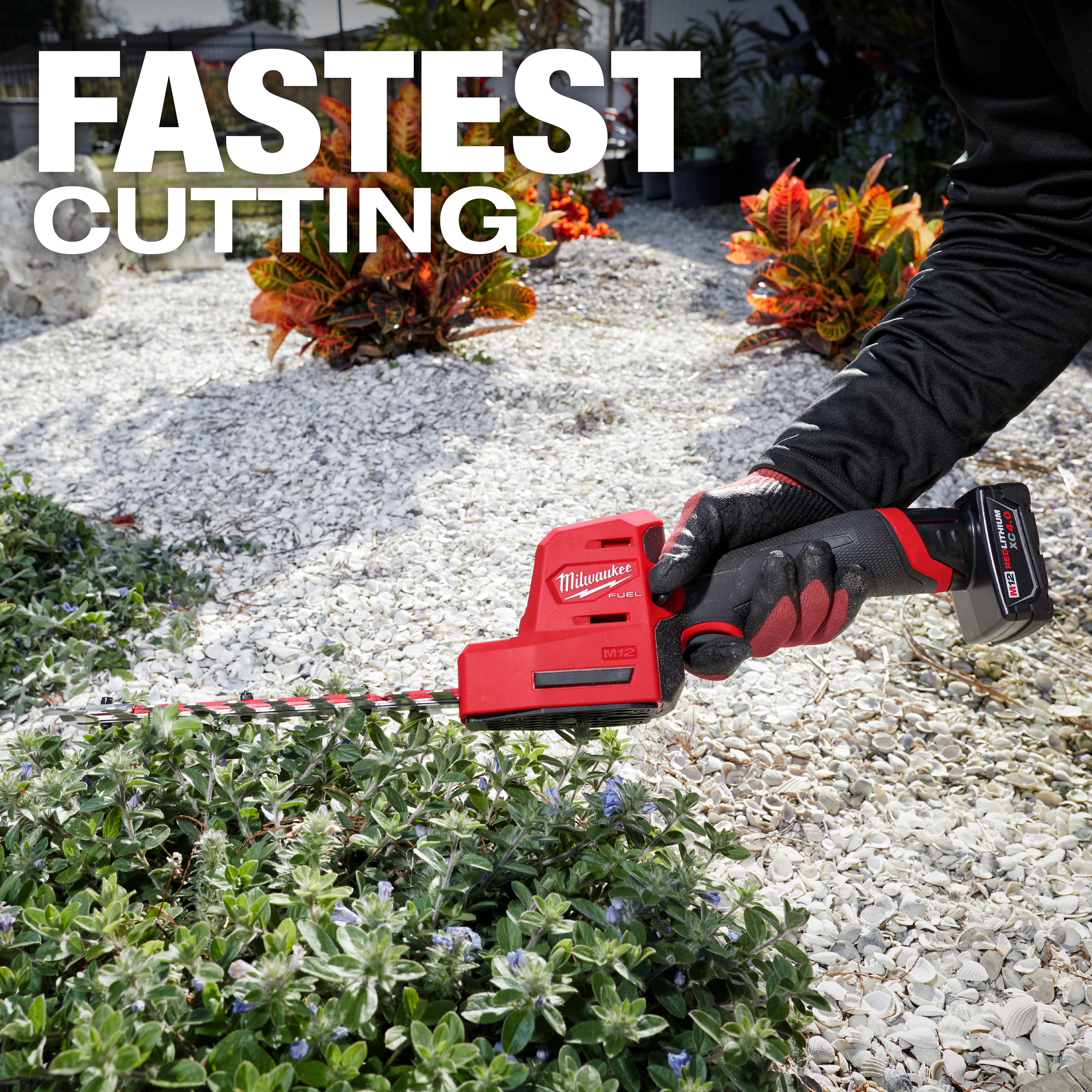 A person is using the M12 FUEL™ 8" Hedge Trimmer to trim a shrub in a garden. The text "FASTEST CUTTING" is prominently displayed at the top of the image. The hedge trimmer is red and black, labeled with the Milwaukee logo.