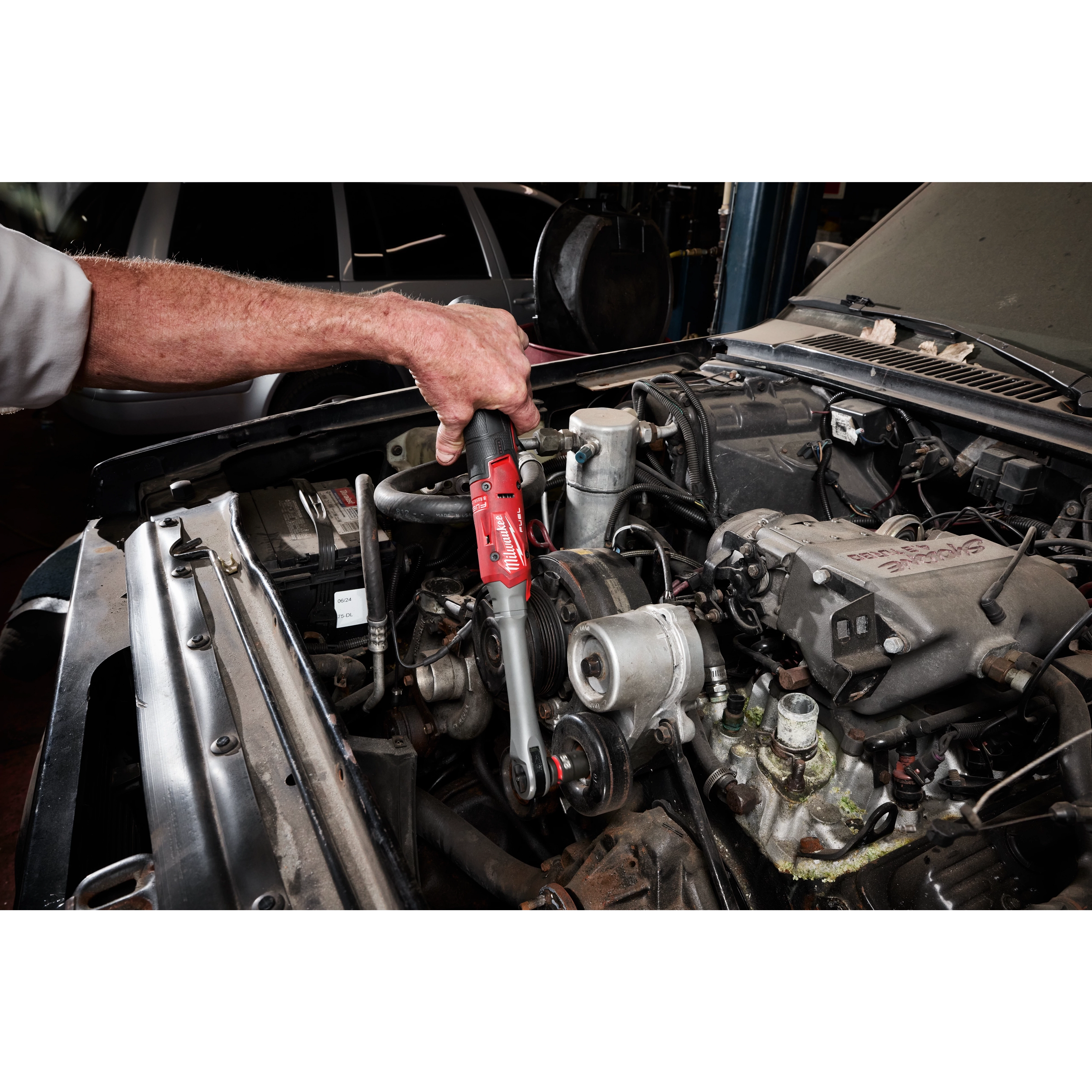 M12 FUEL 1/2" Extended Reach Ratchet being used on an engine component under an open car hood.