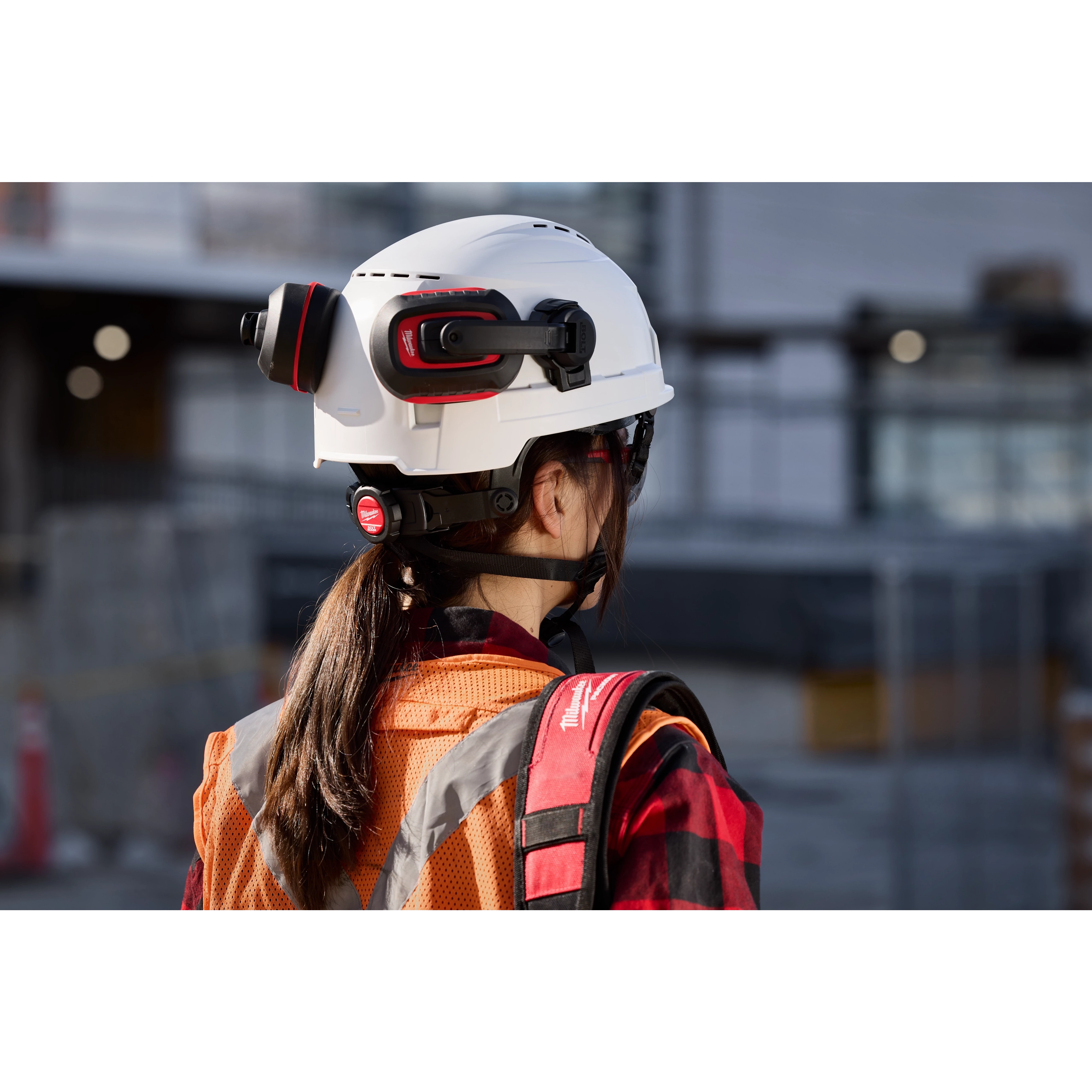 A person wearing a BOLT 4PT White Vented Safety Helmet - Type 2, Class C at a construction site.