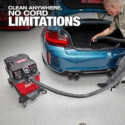Milwaukee M18 FUEL™ NEXUS™ 9 Gallon Dual-Battery Wet/Dry Vacuum is used to clean the trunk of a blue car. The vacuum is red and black, placed next to the car, emphasizing its cordless functionality. Text overlay reads "Clean anywhere, no cord limitations."
