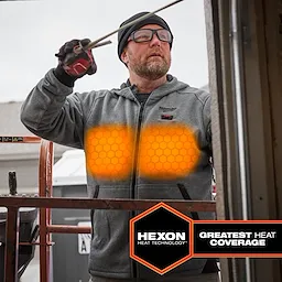 M12™ Heated Hoodie features Hexon Heat Technology for maximum heat coverage, shown with glowing heat zones on the chest. The grey hoodie has a front zipper, two pockets, and the Milwaukee logo on the upper left side. The man's gloves are visible as he works with a tool.