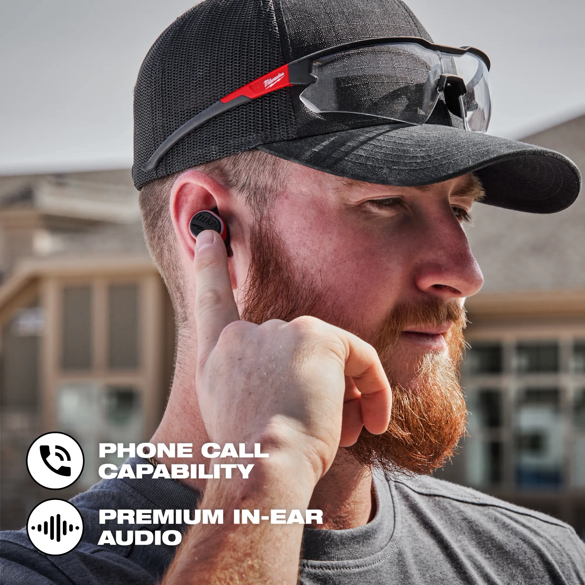Worker on the jobsite using the Bluetooth ear buds to make a phone call