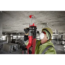 Worker using an SDS Plus DUST TRAP Drilling Shroud Bulk 10 on a red drill to minimize dust while drilling into a concrete ceiling.