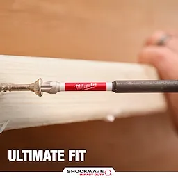 The image shows a Milwaukee SHOCKWAVE™ TORX® Bit being used to drive a screw into wood. The bit has a red and white shaft with the Milwaukee logo. The text "ULTIMATE FIT" and the SHOCKWAVE™ logo are displayed below.