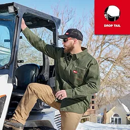 Person wearing a GRIDIRON Flannel Shirt stepping into a work vehicle in a snowy outdoor setting.