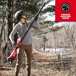 A woman wearing the Women's FREEFLEX™ Hybrid Tee - Long Sleeve is working in a wooded area using a power tool. She is wearing safety gear including a helmet and gloves. The tee features a forward shoulder design.