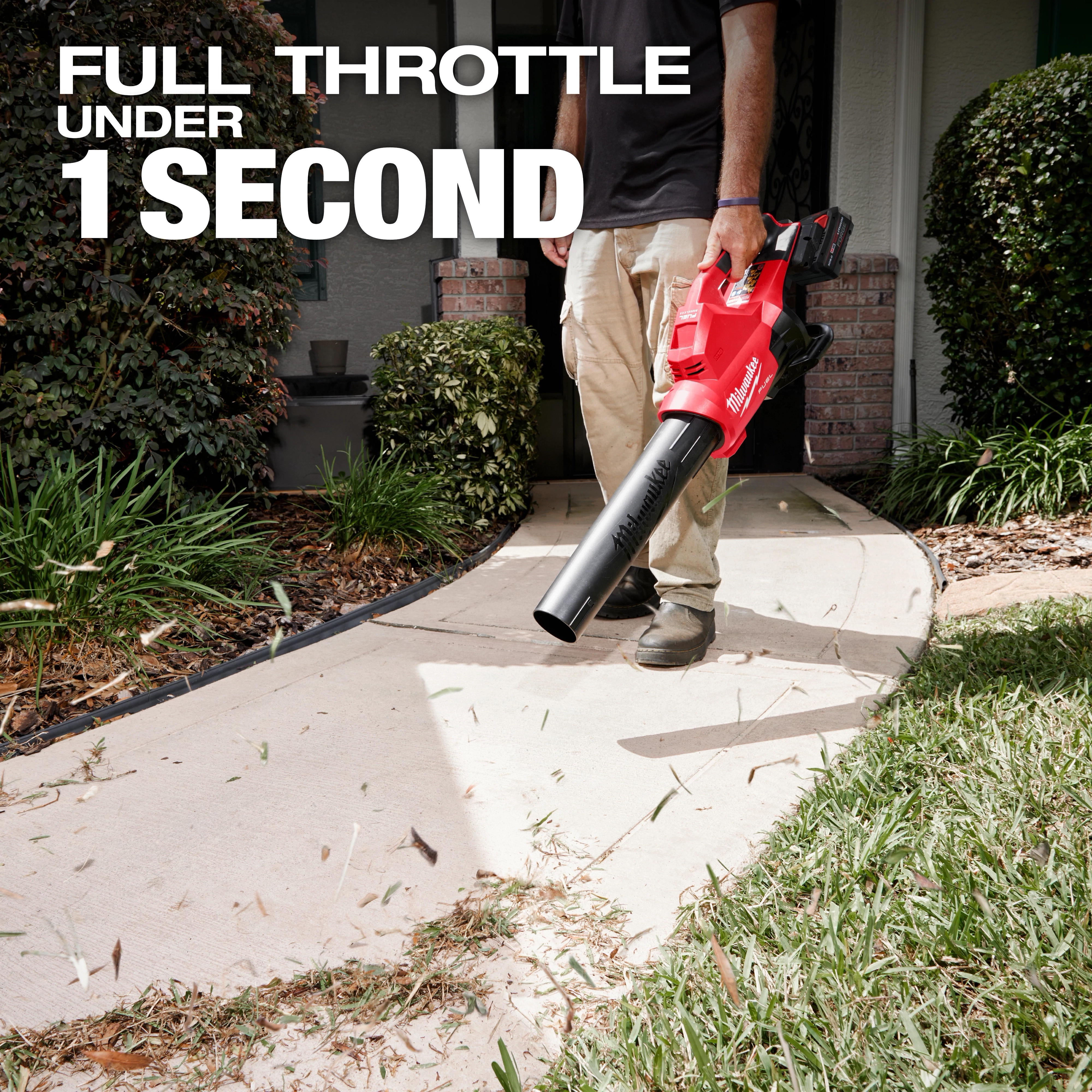 A person uses the M18 FUEL™ Dual Battery Blower to clear debris from a sidewalk. The text on the image reads "Full throttle under 1 second." Shrubs and a house entrance are visible in the background.