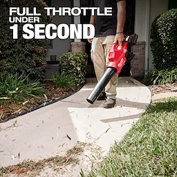A person uses the M18 FUEL™ Dual Battery Blower to clear debris from a sidewalk. The text on the image reads "Full throttle under 1 second." Shrubs and a house entrance are visible in the background.