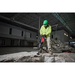 Construction worker using the MX FUEL 27 lb SDS MAX Demolition Hammer to break concrete in an industrial building.
