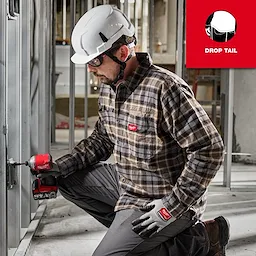 A person in a white hard hat is using a power tool while wearing a GRIDIRON Flannel Shirt, pants, and gloves with a knee pad.
