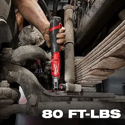 A person is using the M12 FUEL™ 1/2" Ratchet to tighten a bolt in a dirty, tight mechanical environment. The product features a black and red design and operates with a torque power of 80 foot-pounds, as indicated by text in the bottom right corner.