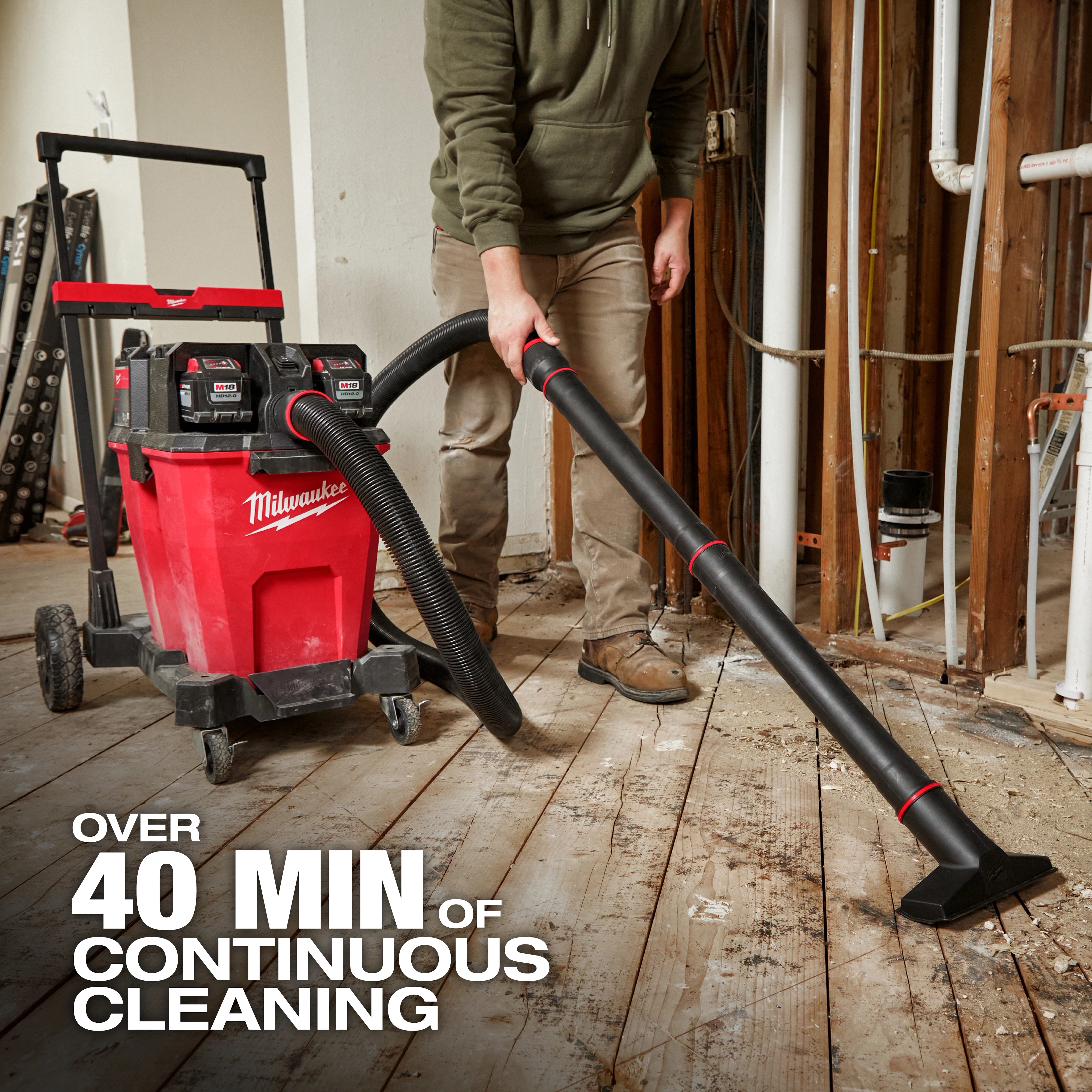 The M18 FUEL™ NEXUS™ 12 Gallon Dual-Battery Wet/Dry Vacuum Kit by Milwaukee is shown being used to clean a construction site. The vacuum is red with black wheels and features two large hose attachments. Text indicates it provides over 40 minutes of continuous cleaning.