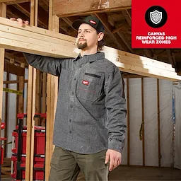 Person carrying lumber in a framed building while wearing a GRIDIRON Flannel Shirt.