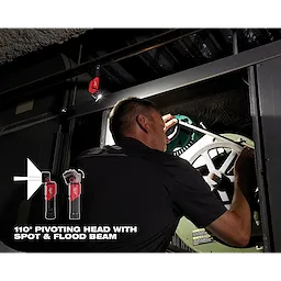 Man using REDLITHIUM USB Pivoting Flashlight to repair machinery in a dark industrial setting, demonstrating its pivoting head and flood beam.