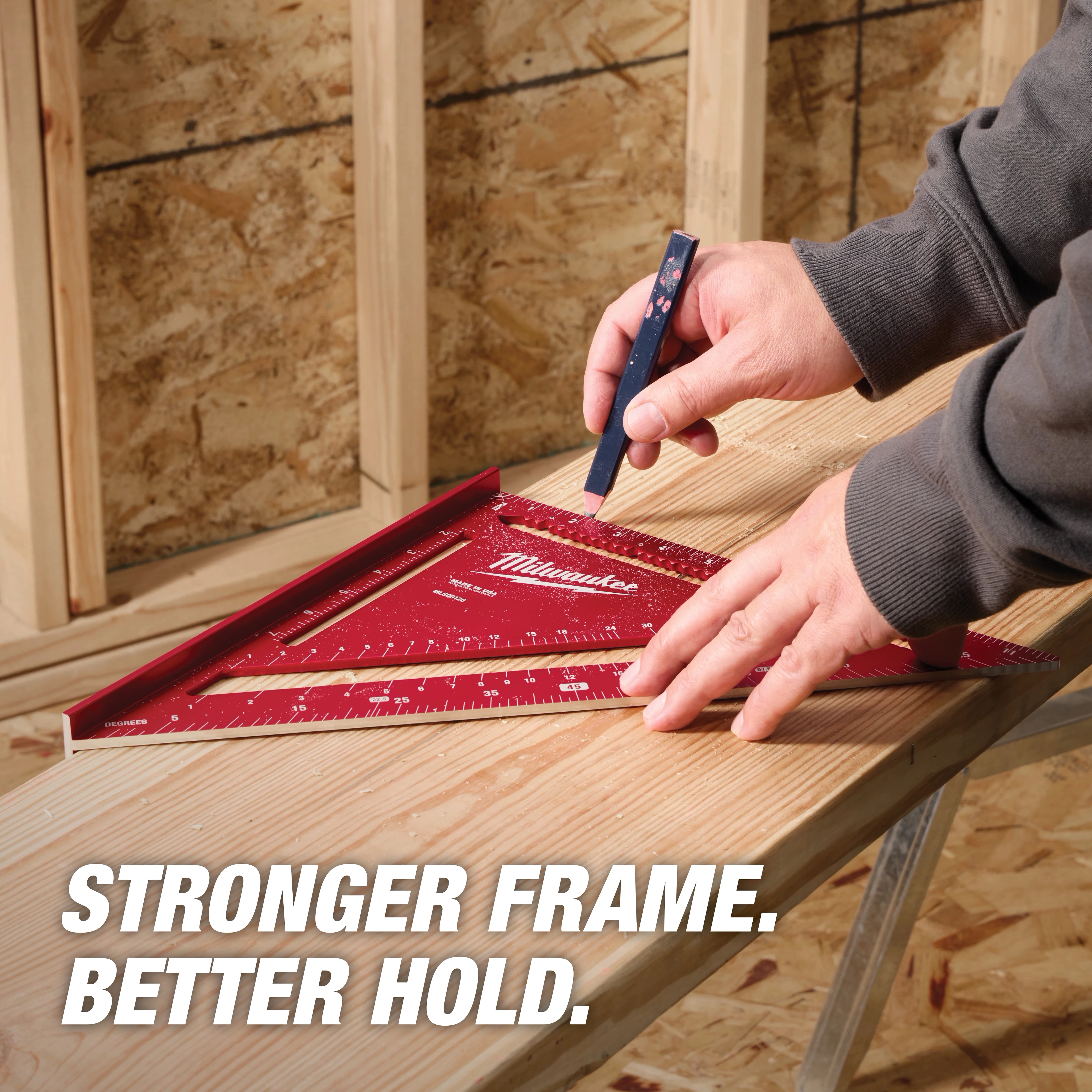 A person marks wood using a red 12" Rafter Square and a pencil. The background shows wooden framing and a partially finished wall. The text "STRONGER FRAME. BETTER HOLD." is displayed in the bottom left corner.