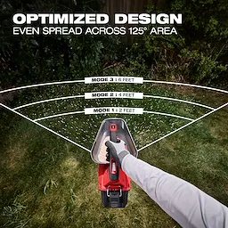 Person using an M12 Handheld Broadcast Spreader to distribute material evenly across a lawn.