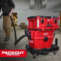The M18 FUEL™ NEXUS™ 6 Gallon Wet/Dry Vacuum w/ PACKOUT™ Compatibility & VACLINK™ is a red, portable vacuum cleaner designed for workshops. It is shown being used by a person in a workshop setting, highlighting its PACKOUT™ stackable storage system compatibility.