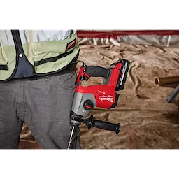 A red and black M18 FUEL™ 5/8" SDS Plus Rotary Hammer is attached to a worker's belt. The image showcases the power tool and the waist area of the worker. The background depicts a construction site.