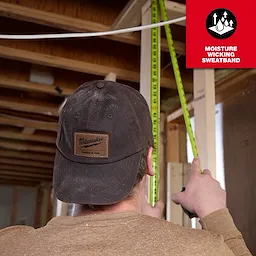 Person measuring in a construction site, wearing a Waxed Canvas Adjustable Hat. Inset text highlights the moisture-wicking sweatband feature.