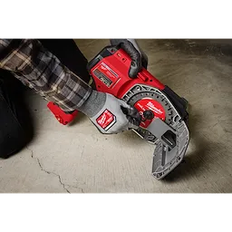 A person wearing work gloves operates a Milwaukee brand M18 FUEL™ ½”-1” Steel Pipe Cutter on a concrete floor. The tool is red and grey, showing the cutter's mechanisms and design features.