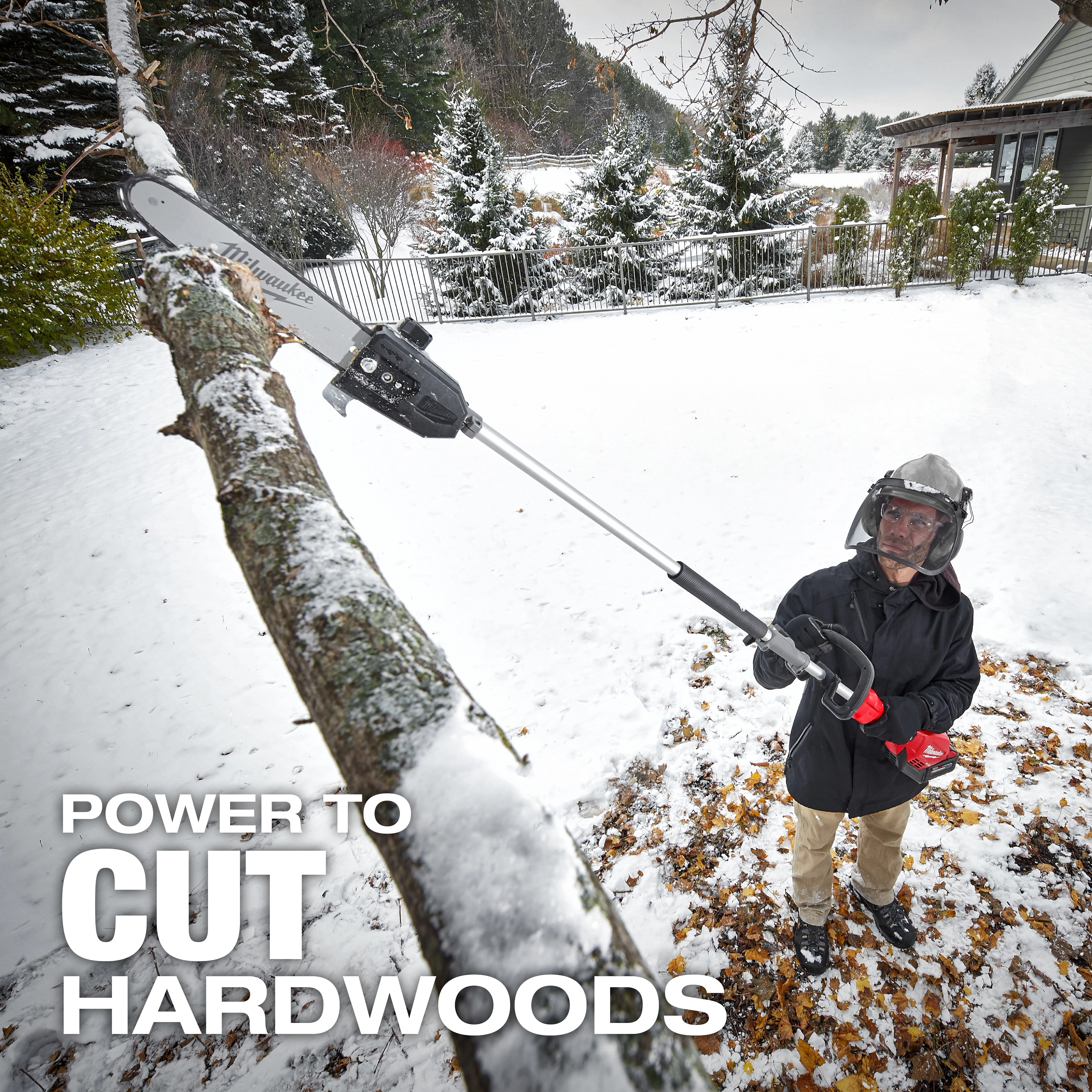 A person is using a pole saw to cut a tree branch in a snowy backyard. The text in the image reads "POWER TO CUT HARDWOODS." The surroundings include a house, trees, and a snow-covered landscape.
