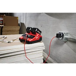 M18 TOP-OFF 350W Power Supply & Charger w/ PACKOUT Compatibility on stacked boards, plugged into a wall outlet.