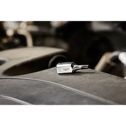 The 3/8" Drive T30 Tamper-Proof TORX Bit Socket is displayed on a gray surface with a blurred background. The small, metal bit socket features a TORX head and is designed for secure, tamper-proof fastener removal.