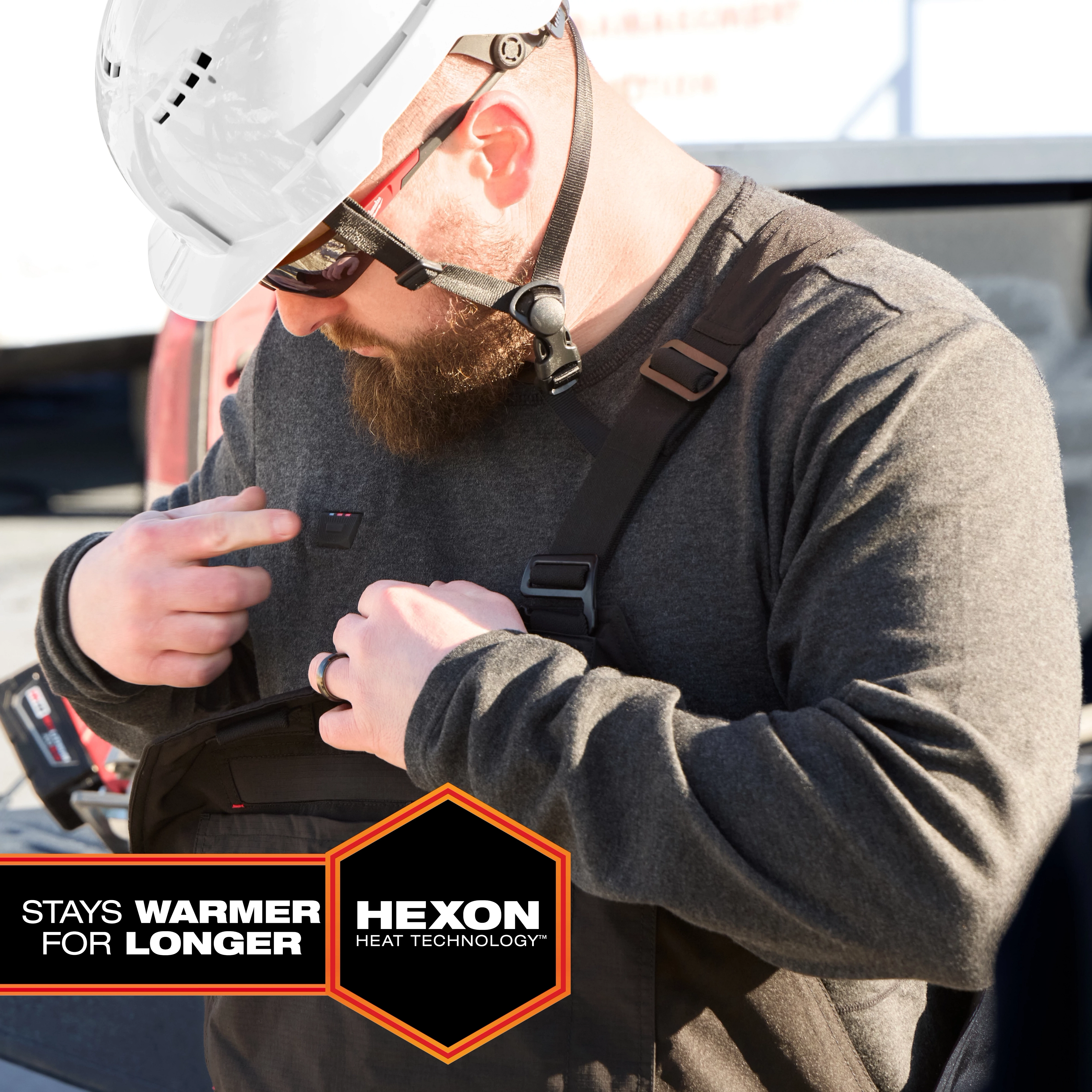 Worker wearing a Milwaukee Heated Merino Wool Crew Neck Baselayer adjusts harness straps outdoors