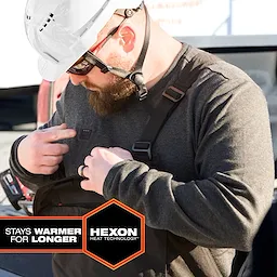 Worker wearing a Milwaukee Heated Merino Wool Crew Neck Baselayer adjusts harness straps outdoors