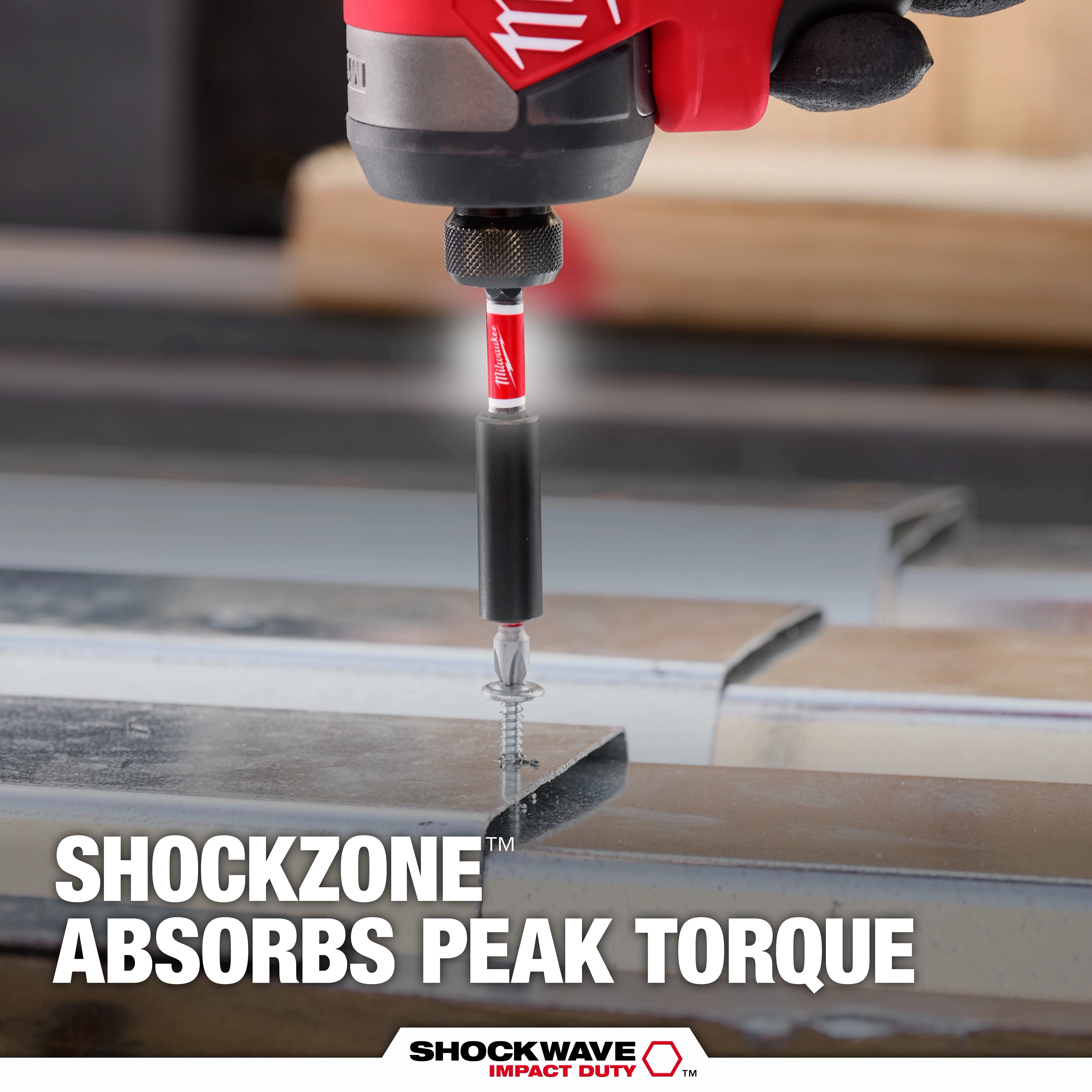 The image shows the SHOCKWAVE™ SHOCKZONE™ Bit Holder being used to drill a screw into metal, with the text "SHOCKZONE™ Absorbs Peak Torque" displayed. The product absorbs torque to prevent bit breakage during drilling.