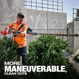 A person wearing an orange safety vest uses a hedge trimmer to cut green shrubs
