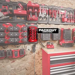 A Power Manager – 15 Amp Circuit, 20 Amp Circuit is mounted on a workshop wall, surrounded by various power tools, chargers, and tool storage solutions. The image shows the organized setup and highlights the device's compatibility with PACKOUT storage systems.